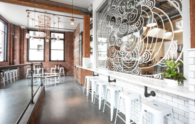 Interior of Quebec street location of Earnest Ice Cream scoop shop. Glass wall with cloud motifs and bar stools, windows in background.