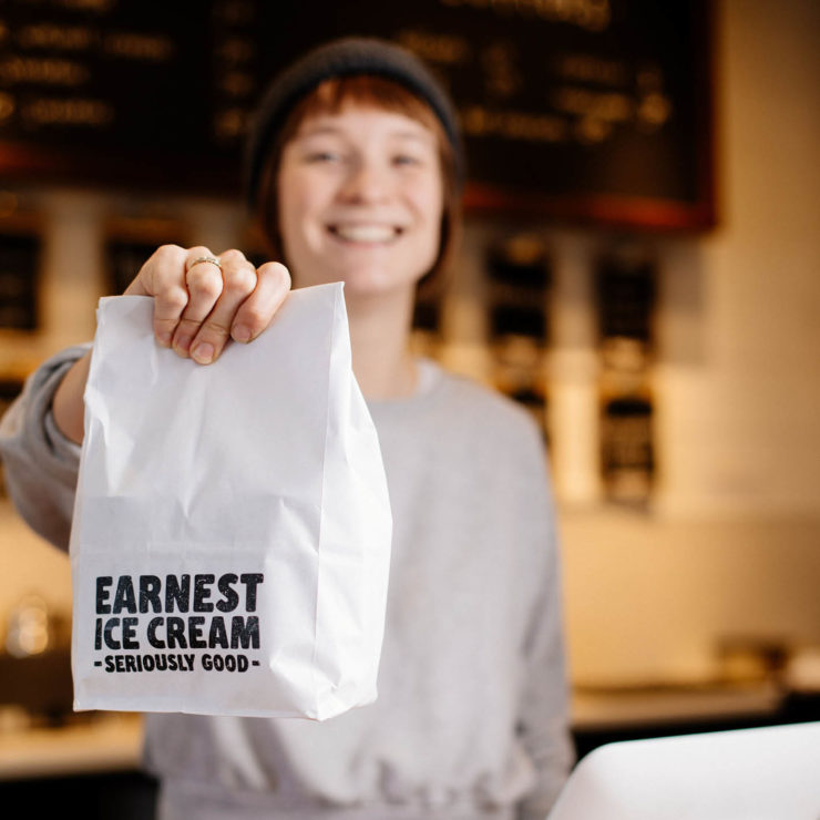 Earnest Icecream employee with a white takeaway bag of ice cream treats.