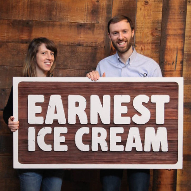 Founders of Earnest Ice Cream with large company sign carved in wood.